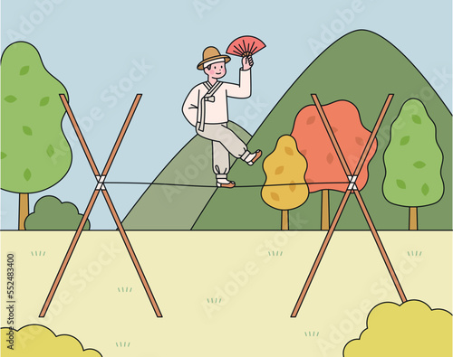 A traditional Korean circus, tightrope walker stands with one foot on the rope with a fan in one hand.