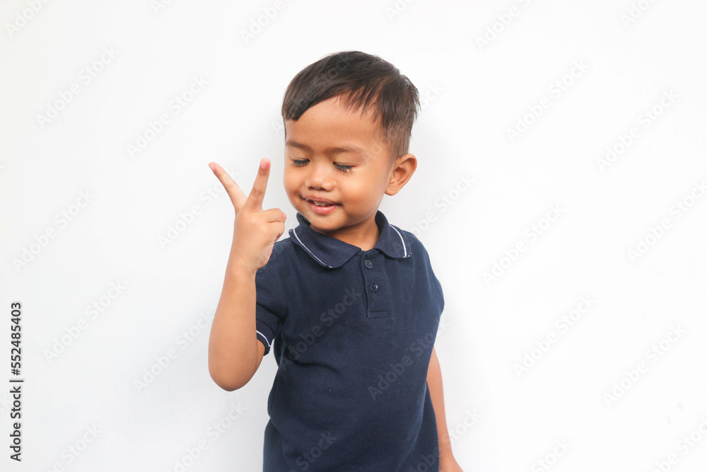 Portrait of adorable toddler showing two fingers while closing the eyes Portrait of adorable toddler showing two fingers while closing the eyes