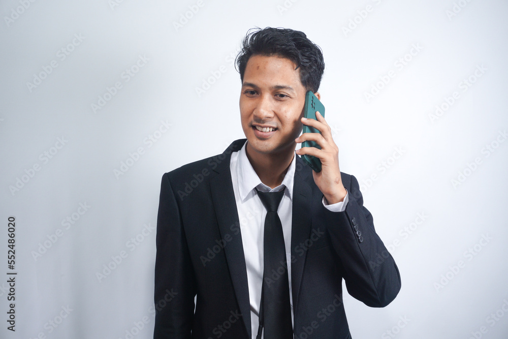 Young Asian Man is confused and shocked when calling in the phone. Indonesian man wearing a black suit. Young Asian Man is confused and shocked when calling in the phone. Indonesian man wearing a black suit.