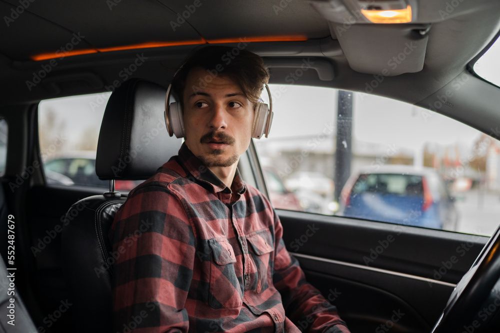 man with headphones listen music or podcast in car use mobile phone