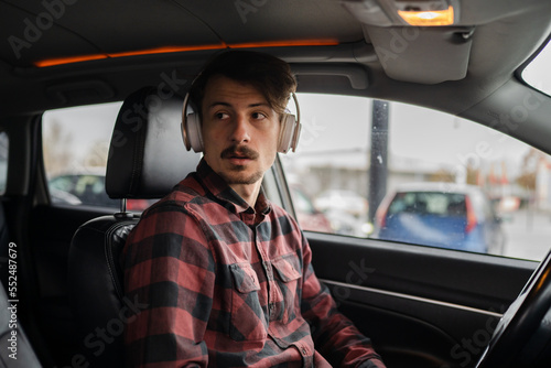 man with headphones listen music or podcast in car use mobile phone © Miljan Živković