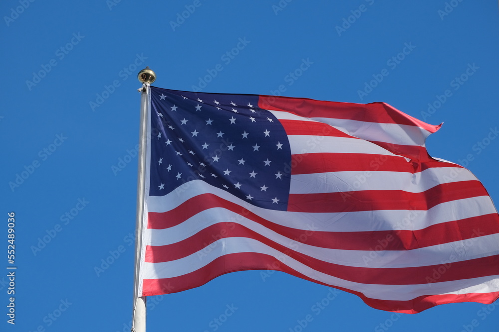 Fototapeta premium US flag waves into blue sky