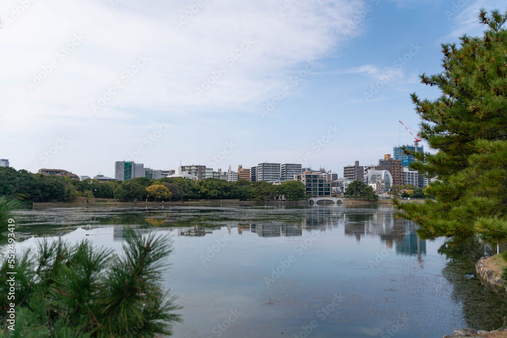 view of city town skyline over the pond lake natural view under daytime in japan, big city with natural lake public