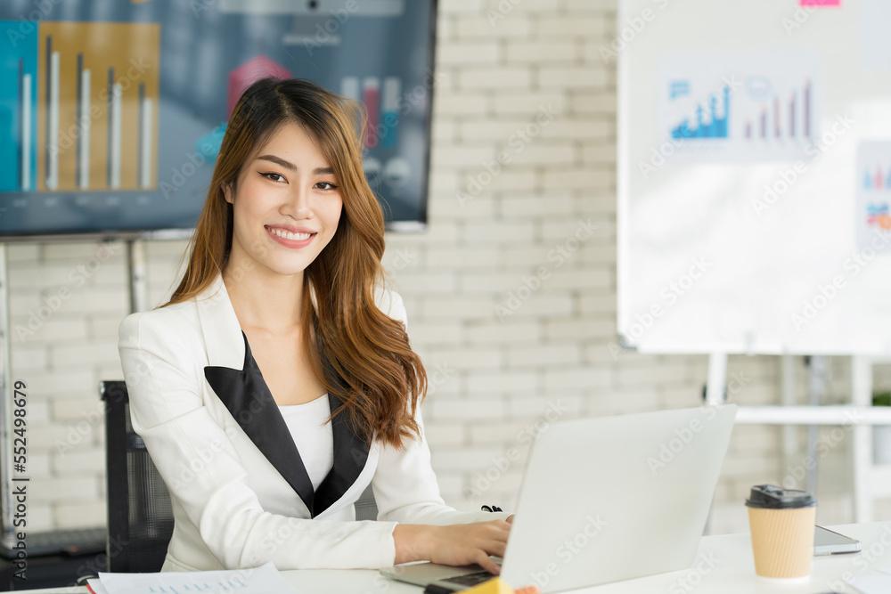 Asian business woman working with laptop computer in the office. Smiling Asian business woman in the office Asian business woman working with laptop computer in the office. Smiling Asian business woman in the office