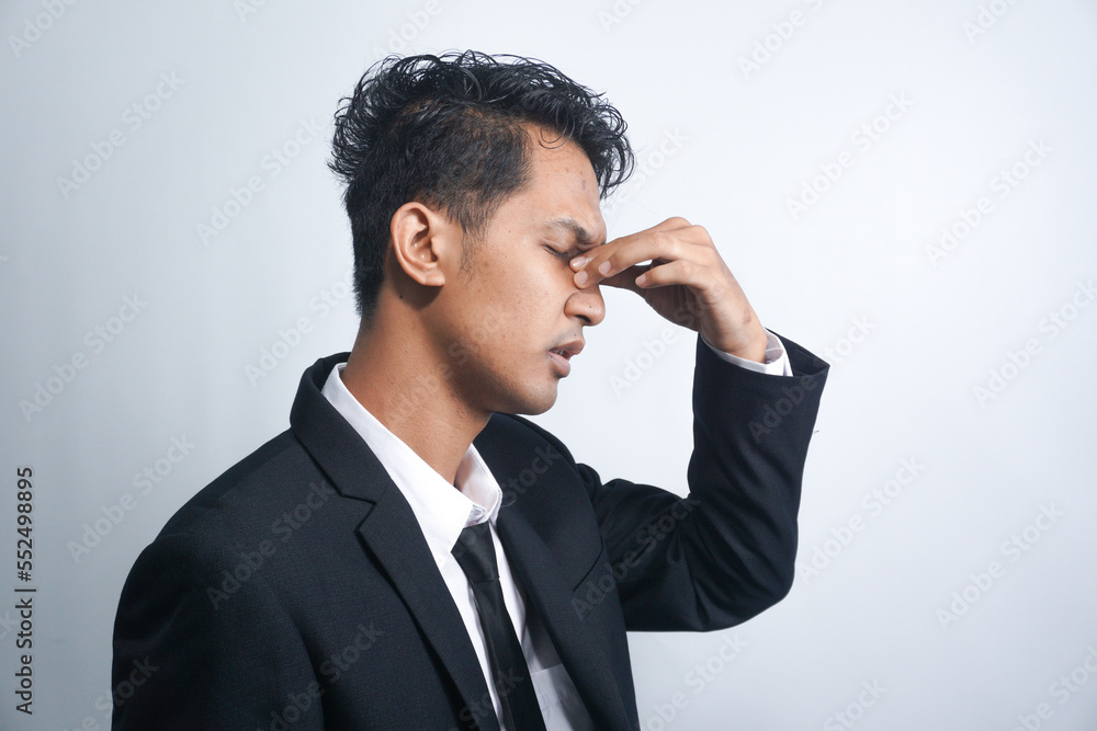 Asian young man stress tired and holding his nose suffer sinus pain fatigue from hard work. Asian young man stress tired and holding his nose suffer sinus pain fatigue from hard work.