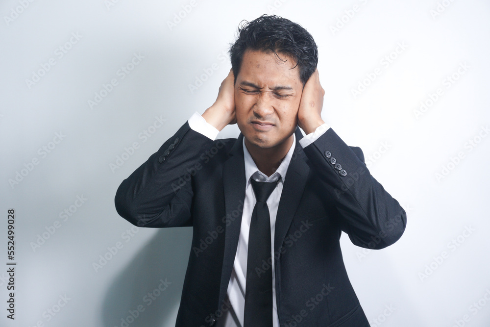 young handsome asian man looking angry, stressed and annoyed, covering both ears to a deafening noise, sound or loud music young handsome asian man looking angry, stressed and annoyed, covering both ears to a deafening noise, sound or loud music