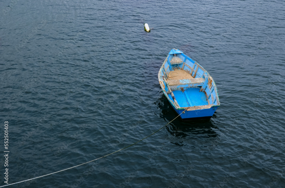 Rustic, bright blue rowboat anchored at sea