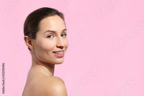 Studio portrait of a young woman with nude makeup on. Female model posing over isolated pink background. Close up, copy space.