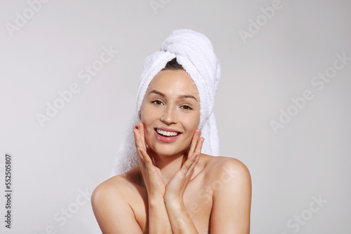 Studio portrait of young beautiful woman wearing hair towel wrap after bathing. Close up  copy space  isolated gray background.