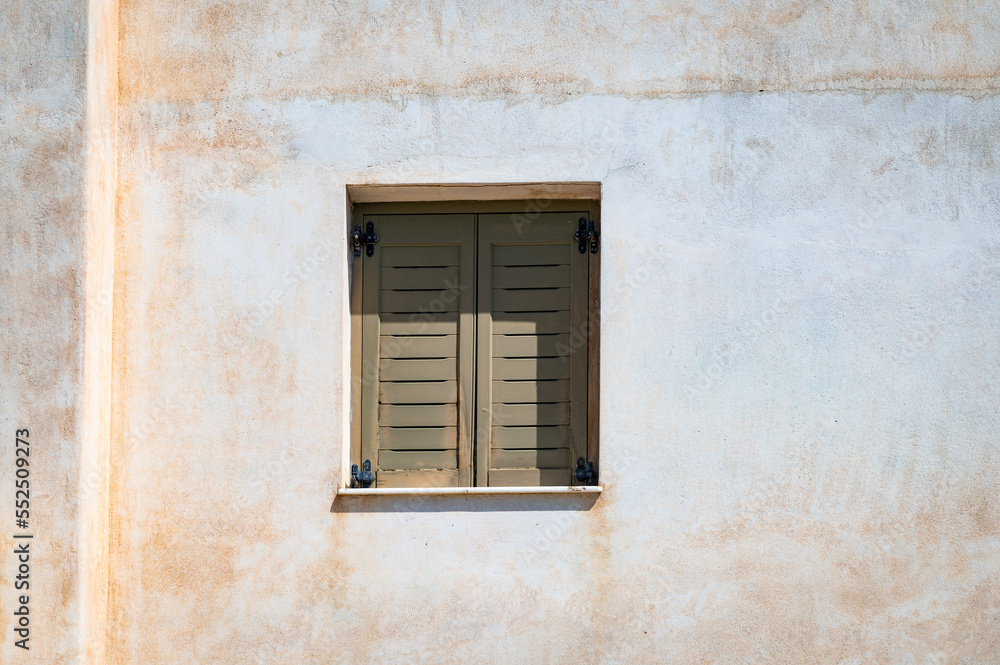 Photo of a shuttered window on the side of a house in a small town on the Greek island or Paros.