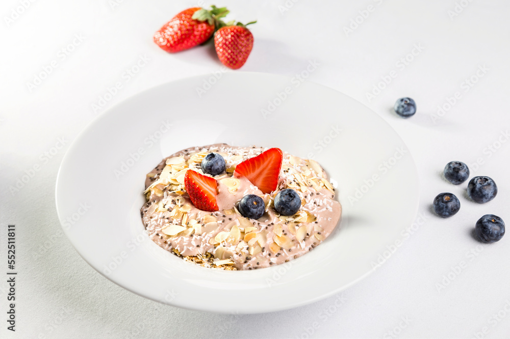 Oatmeal with almonds, blueberries and strawberries in a white plate on a white background Oatmeal with almonds, blueberries and strawberries in a white plate on a white background