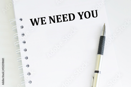 We Need You inscription on a notebook on a table with a pen, a business concept