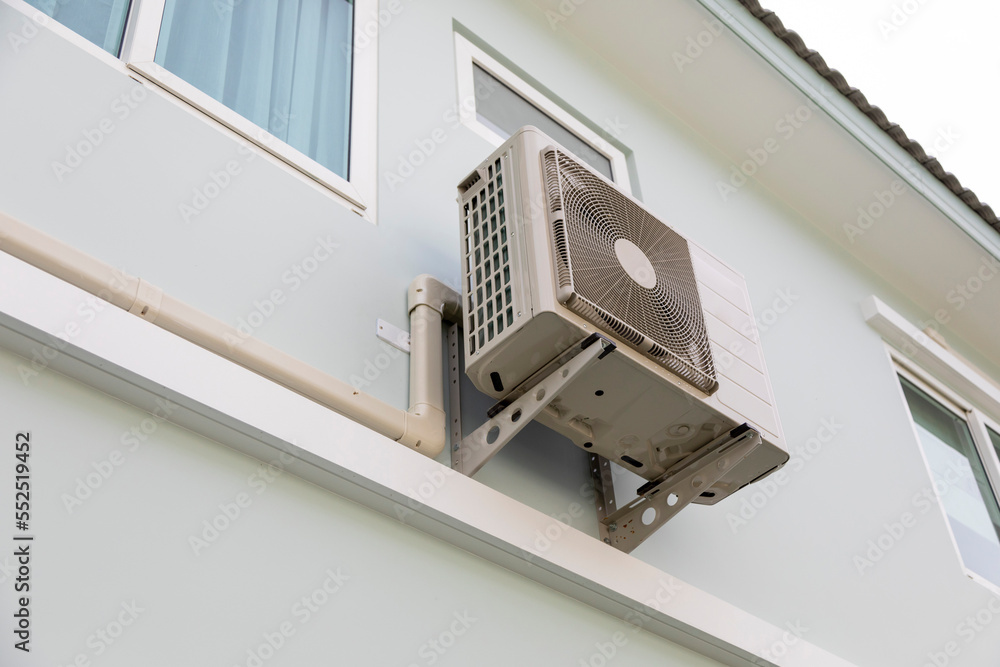 The compact air compressor unit is hanging on wall of the house. The compact air compressor unit is hanging on wall of the house.