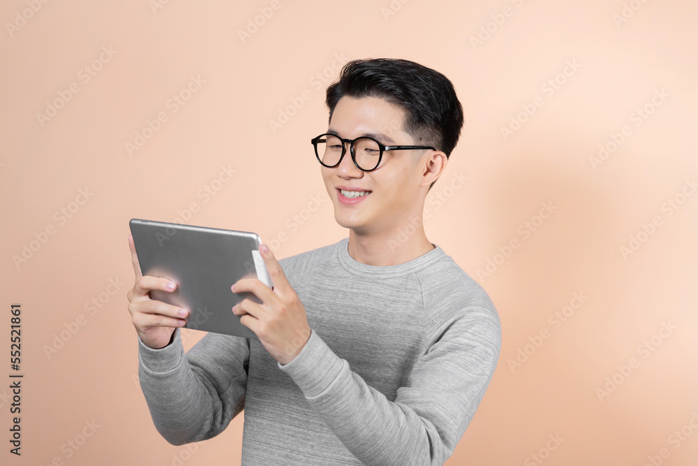 Happy Young Man Using Digital Tablet Isolated On beige Background Happy Young Man Using Digital Tablet Isolated On beige Background