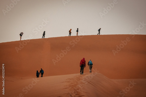 Touristen wandern über einen Grat in Richtung des nebelverhangenen Gipfels der Düne Big Daddy im Sossusvlei (Namibia)