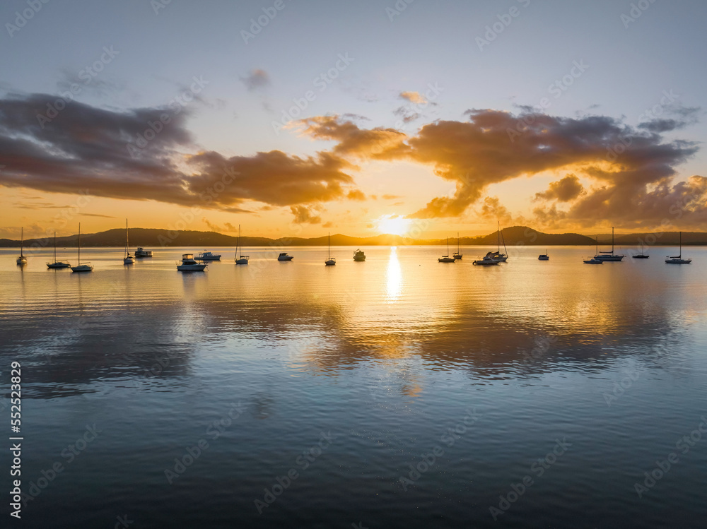 Aerial sunrise waterscape with boats, clouds and reflections