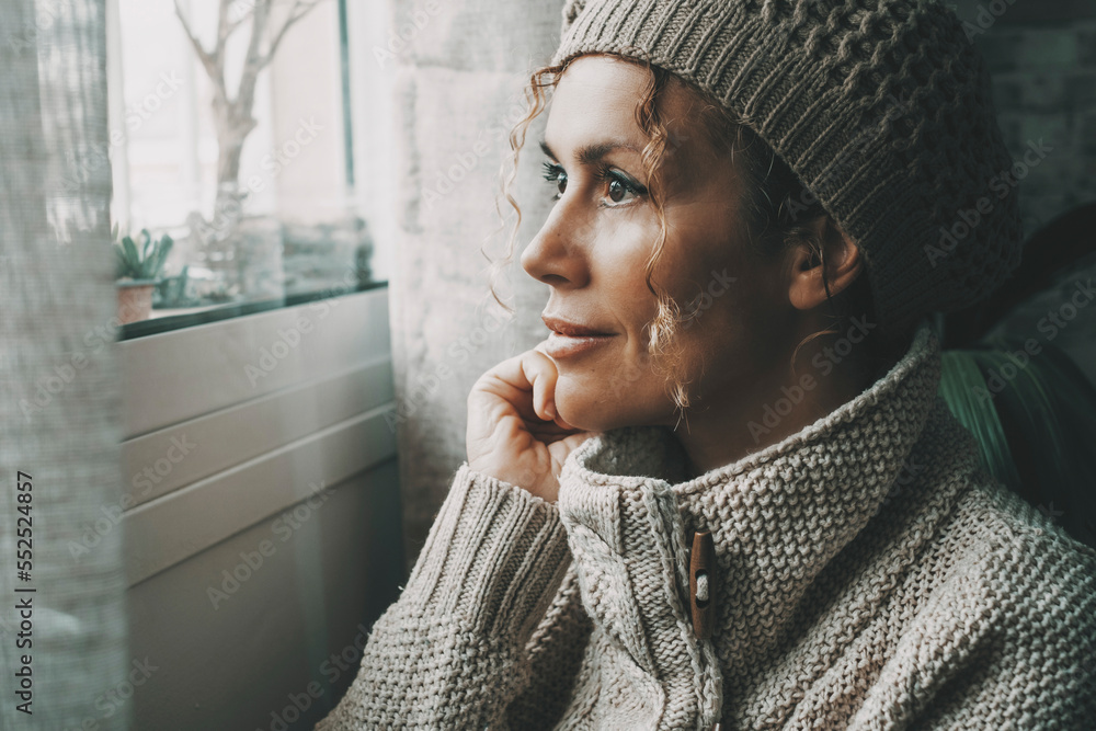 Φωτογραφία Side portrait of serene female looking outside the window at home in winter season Cold house temperature