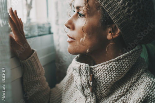 Obraz na plátně Loneliness concept emotion with one adult woman looking outside the window with sad expression