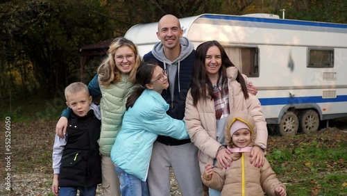 Portrait of a big happy family in the autumn forest on the background of a mobile trailer. A family with children travels in a trailer-a house on wheels.