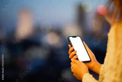 Close up of female hands using mobile smartphone in bright yellow bokeh lights in night city.