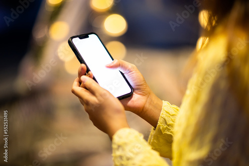 Close up of female hands using mobile smartphone in bright yellow bokeh lights in night city.