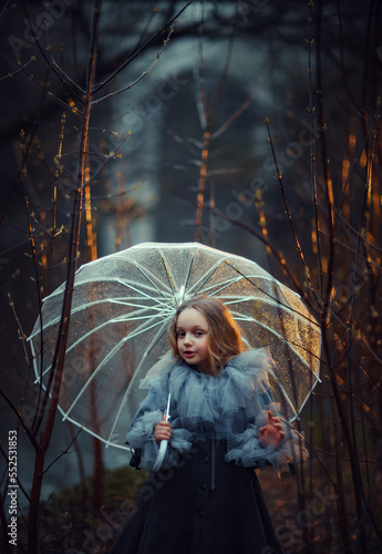 Girl with umbrella in the night forest, vertical photo in warm dark colors with backlight. photo