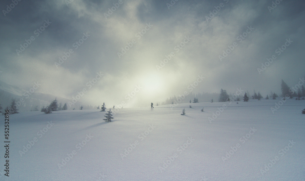 Upslope fog and lonely skier landscape photo. Beautiful nature scenery photography with sunlight on background. Idyllic scene. High quality picture for wallpaper, travel blog, magazine, article