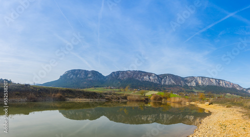 long high mountain with reflections in a pond and blue sky in autumn panorama