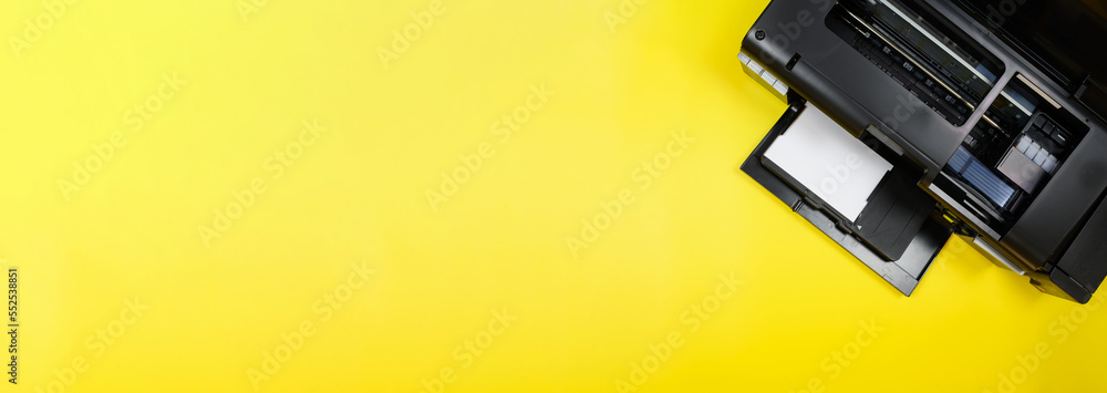 Obraz premium Top view, layout, banner on photo printer and blank sheet of photo paper on yellow background