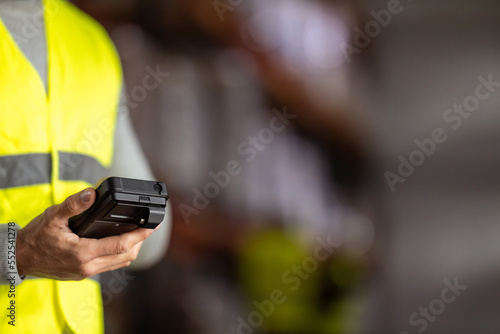 Close-up of a barcode reader in a hand of a man in a reflective uniform.
