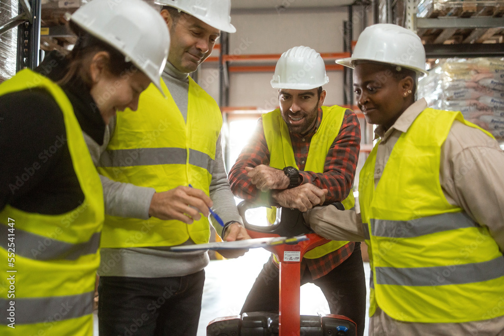 A manager in a distribution warehouse is giving instructions to the workers. They are smiling and ready for work. A manager in a distribution warehouse is giving instructions to the workers. They are smiling and ready for work.