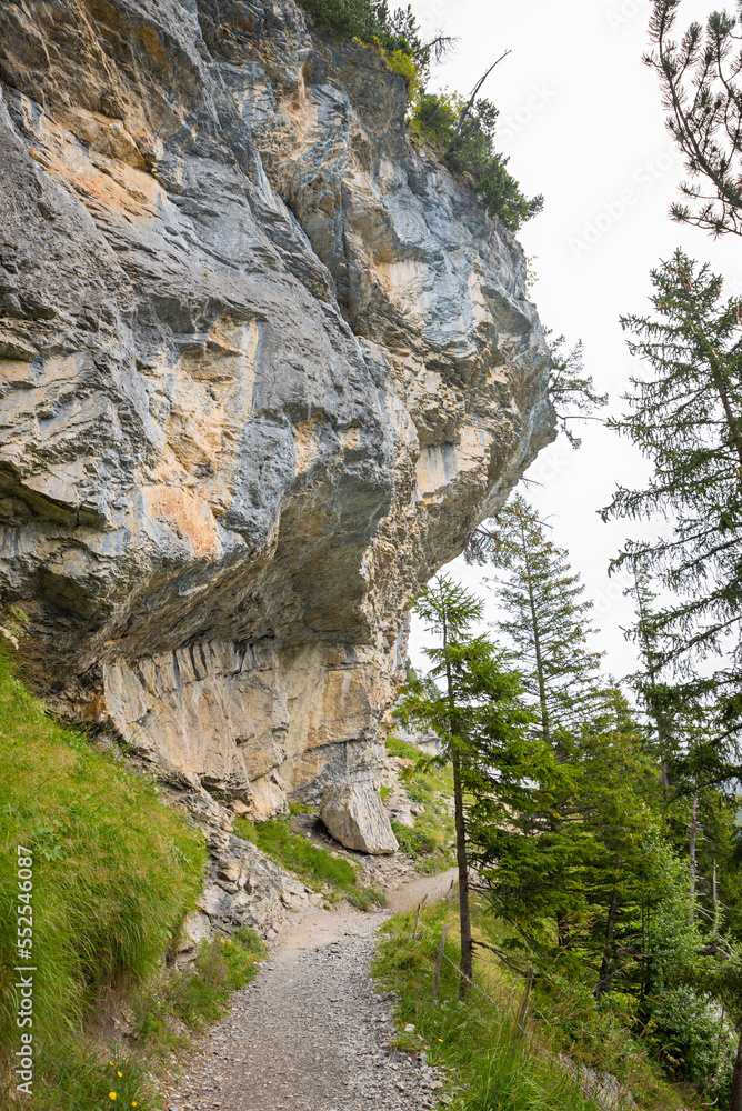 hiking trail around lake Oeschinensee, under overhanging rocks