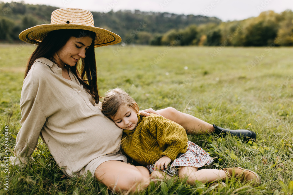 Toddler leaning on her pregnant mother belly, hugging, listening to what is inside the belly. Big sister concept. Toddler leaning on her pregnant mother belly, hugging, listening to what is inside the belly. Big sister concept.