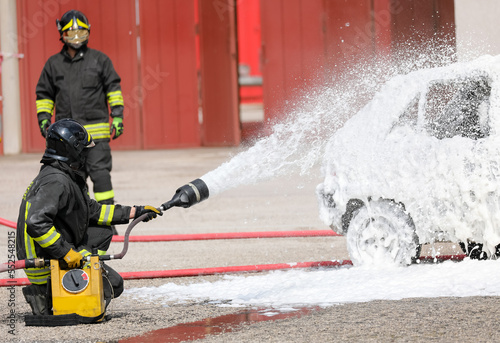 firefighter with a white foam extinguish the fire in the car after the traffic accident