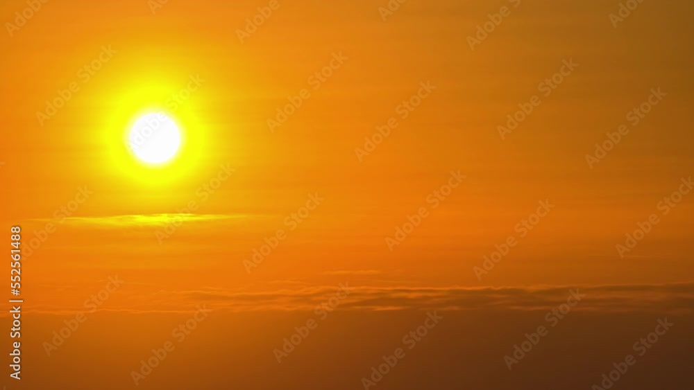 Bright, fiery, yellow sun as it descends through the sunset haze in a golden time lapse Bright, fiery, yellow sun as it descends through the sunset haze in a golden time lapse