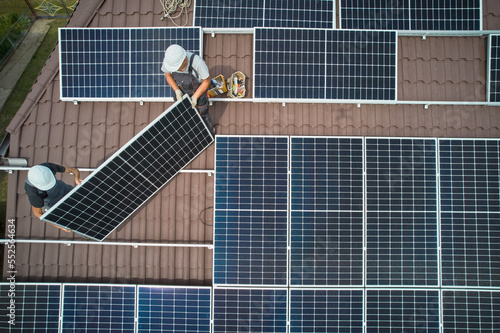 Valokuvatapetti Men workers installing photovoltaic solar moduls on roof of house