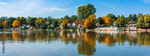 River Tisza and tiny houses at its riverbank in autumn. Beautiful seasonal landscape from Vojvodina, Serbia. photo