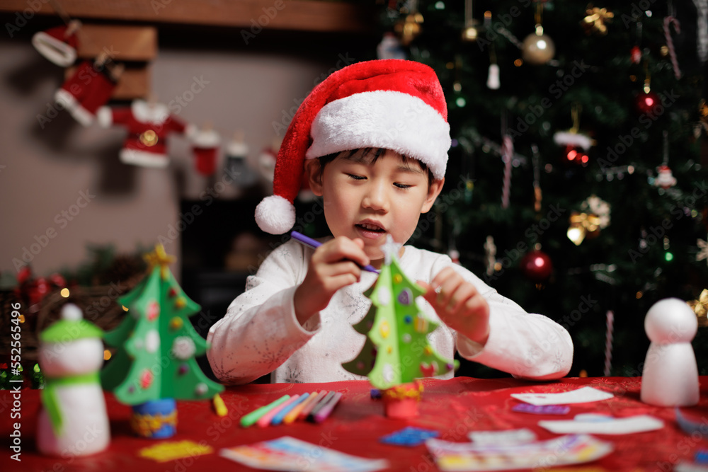 young girl wearing Santa hat was making Christmas craft at home young girl wearing Santa hat was making Christmas craft at home