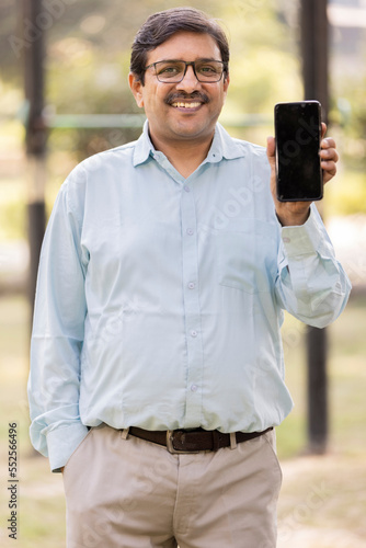 Happy senior man showing mobile phone screen.