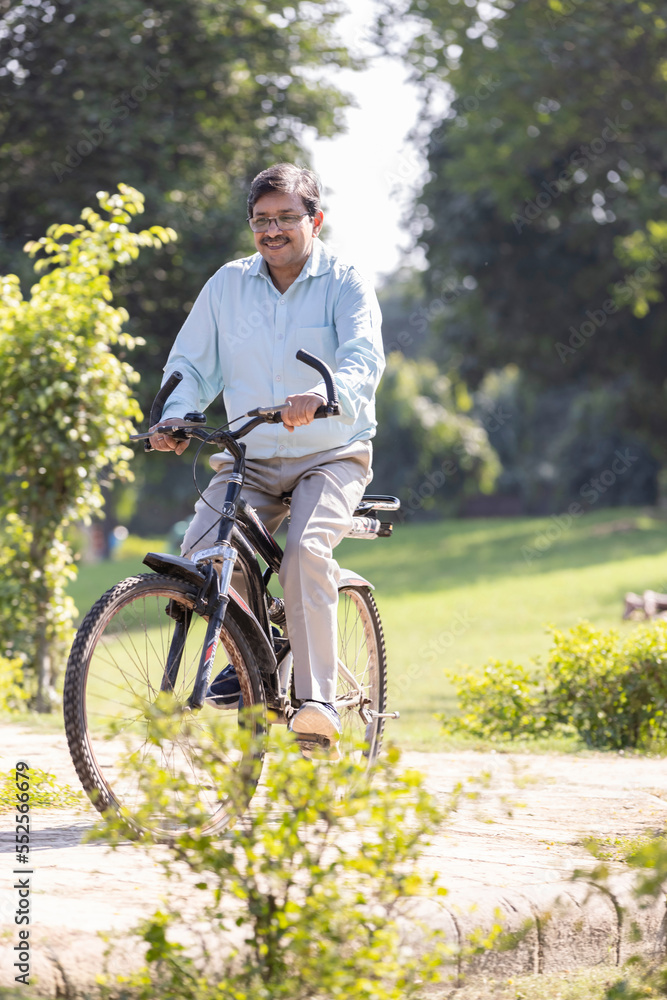 Senior man enjoying and having fun riding bicycle at park