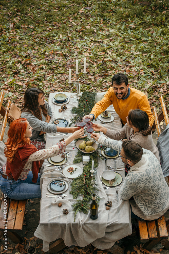 Top view of a group of friends toasting to each other red wine, having a beautiful common garden dinner, and having a great time. Top view of a group of friends toasting to each other red wine, having a beautiful common garden dinner, and having a great time.