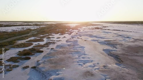 moving aerial view of a salt field,  with little vegetation and a sunset sky photo