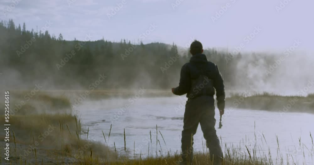 Fisherman looking for fish in swamp with fog in early morning Fisherman looking for fish in swamp with fog in early morning
