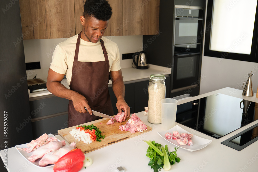 Young african man de-boning chicken to prepare a recipe in a kitchen. Young african man de-boning chicken to prepare a recipe in a kitchen.