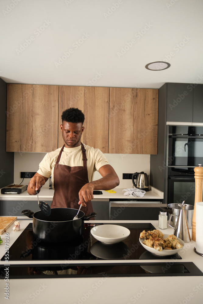 Young african man preparing fried chicken mince with vegetables recipe in a kitchen. Young african man preparing fried chicken mince with vegetables recipe in a kitchen.