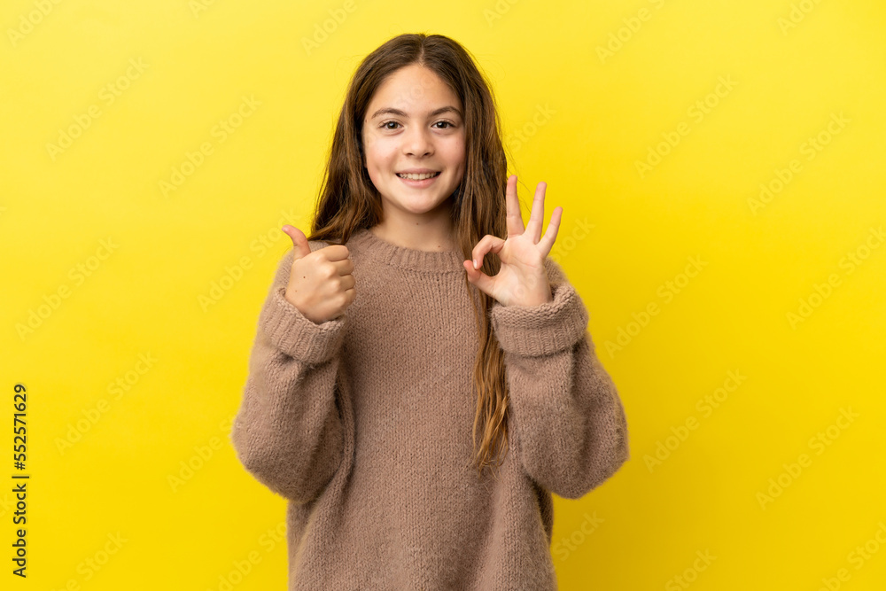 Little caucasian girl isolated on yellow background showing ok sign and thumb up gesture Little caucasian girl isolated on yellow background showing ok sign and thumb up gesture