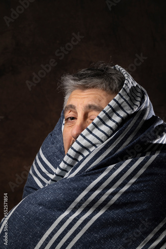 portrait amusant d'un homme recroquevillé sous sa couverture et qui grelotte car il a très froid ou bien parce qu'il est malade photo