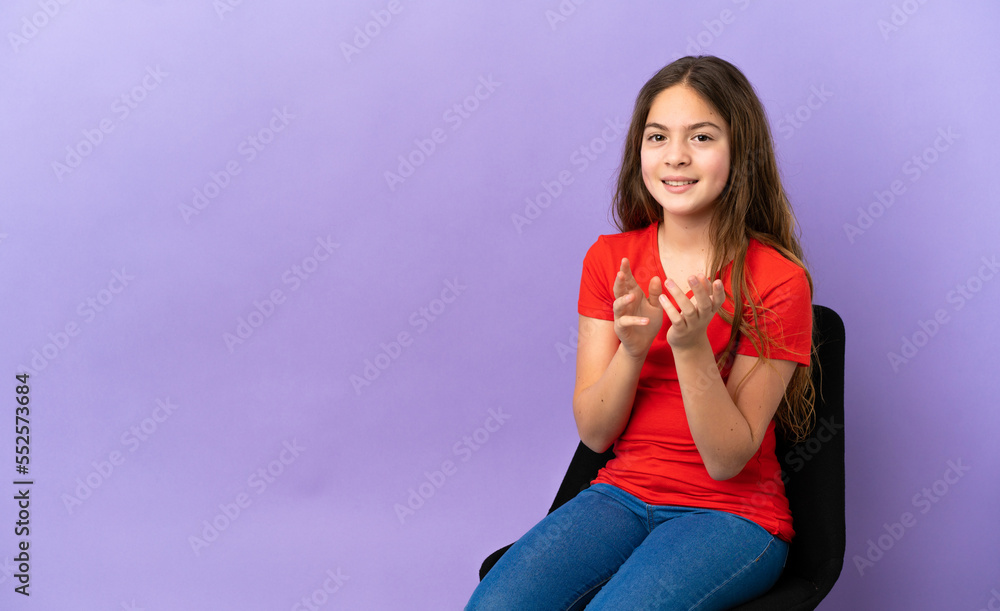 Little caucasian girl sitting on a chair isolated on purple background applauding after presentation in a conference Little caucasian girl sitting on a chair isolated on purple background applauding after presentation in a conference