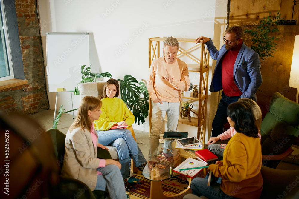 Group of employees, men and women, having meeting, discussion of ideas at the office, indoors. Project launching. Concept of business, brainstorming, conference Group of employees, men and women, having meeting, discussion of ideas at the office, indoors. Project launching. Concept of business, brainstorming, conference