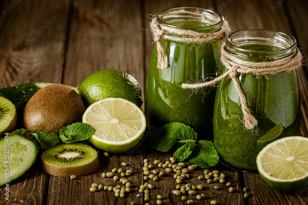 Blended green smoothie with ingredients on the wooden table selective focus. Healthy food. 